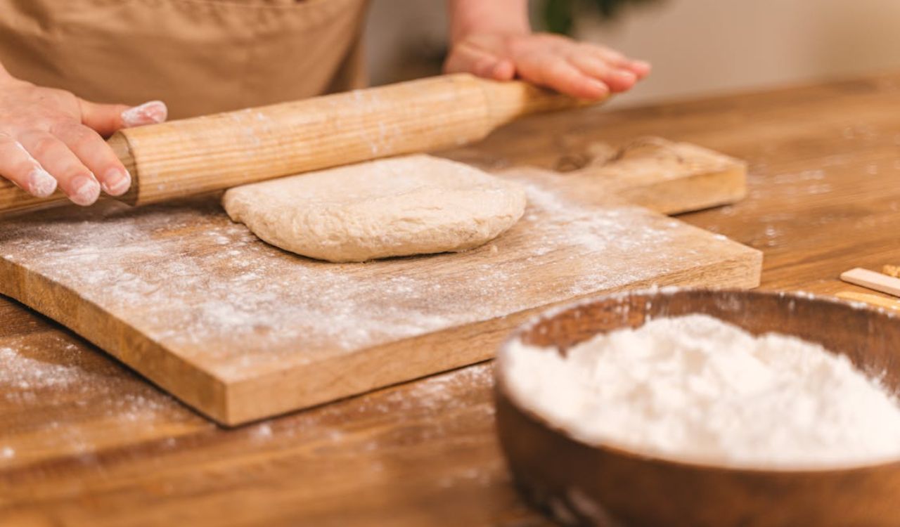 Person Kneading a Dough with a Wooden Rolling Pin