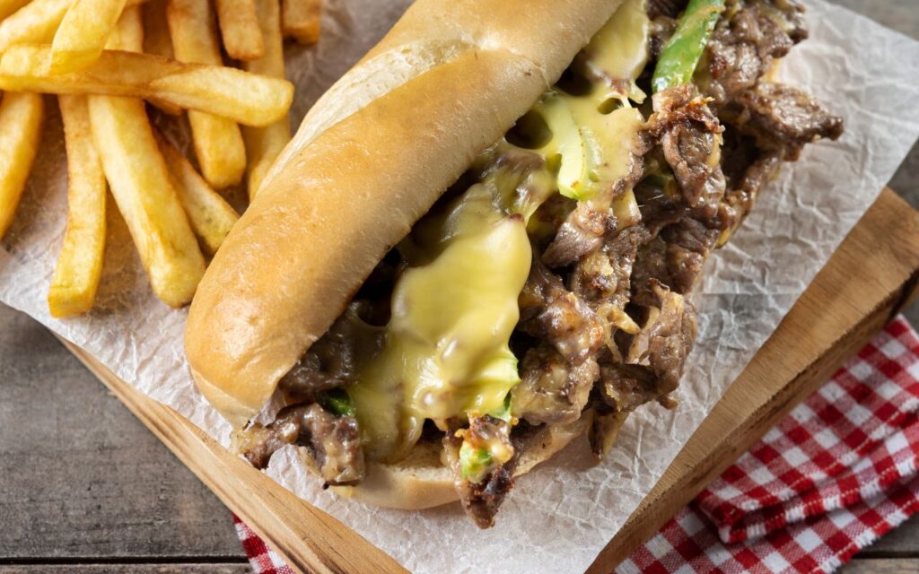 Philly cheesesteak sandwich with melted cheese and fries