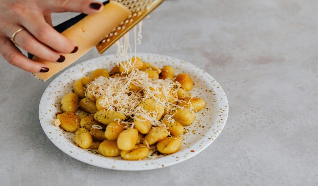 A Person Grating Cheese on a Gnocchi