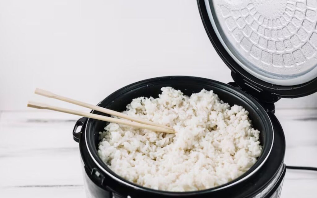 Rice cooker with cooked rice and chopsticks