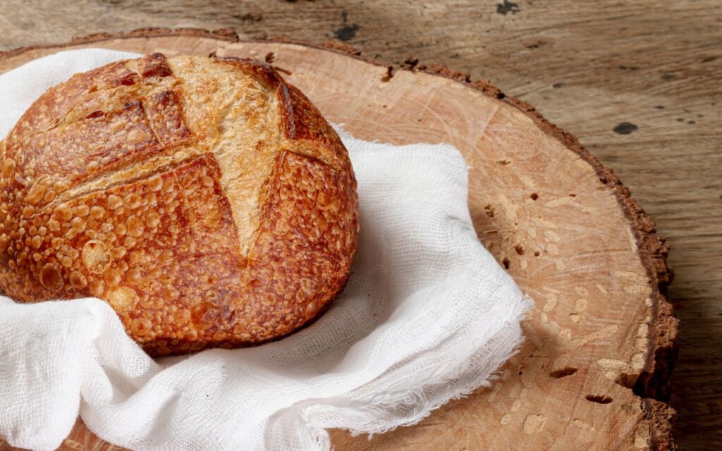 Round loaf of crusty sourdough bread on cloth