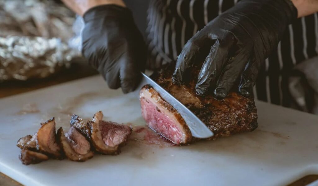 Close-Up Shot of a Person Slicing Cooked Meat