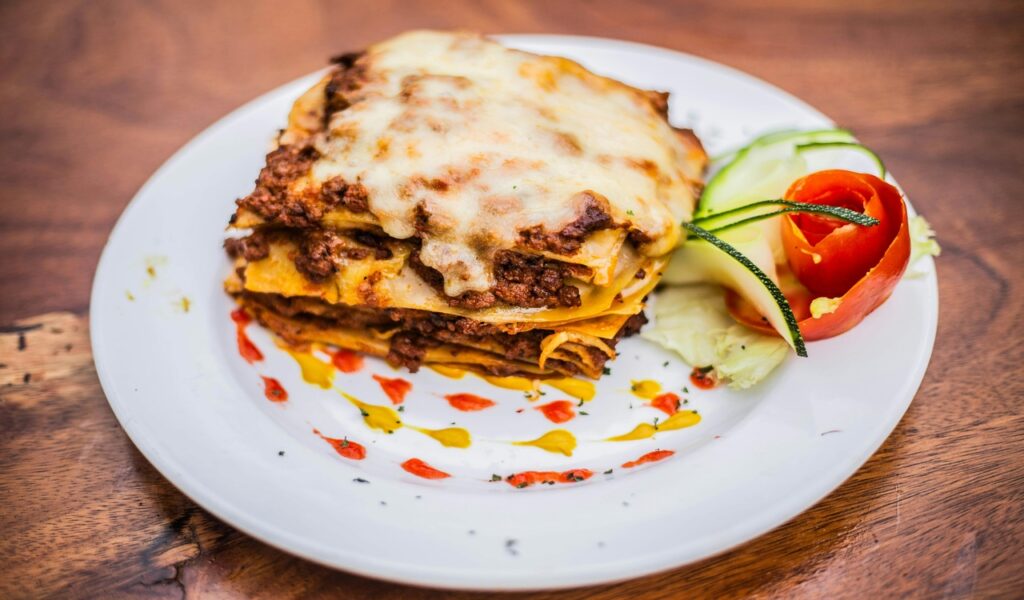 A plate topped with a lasagna and tomato sauce