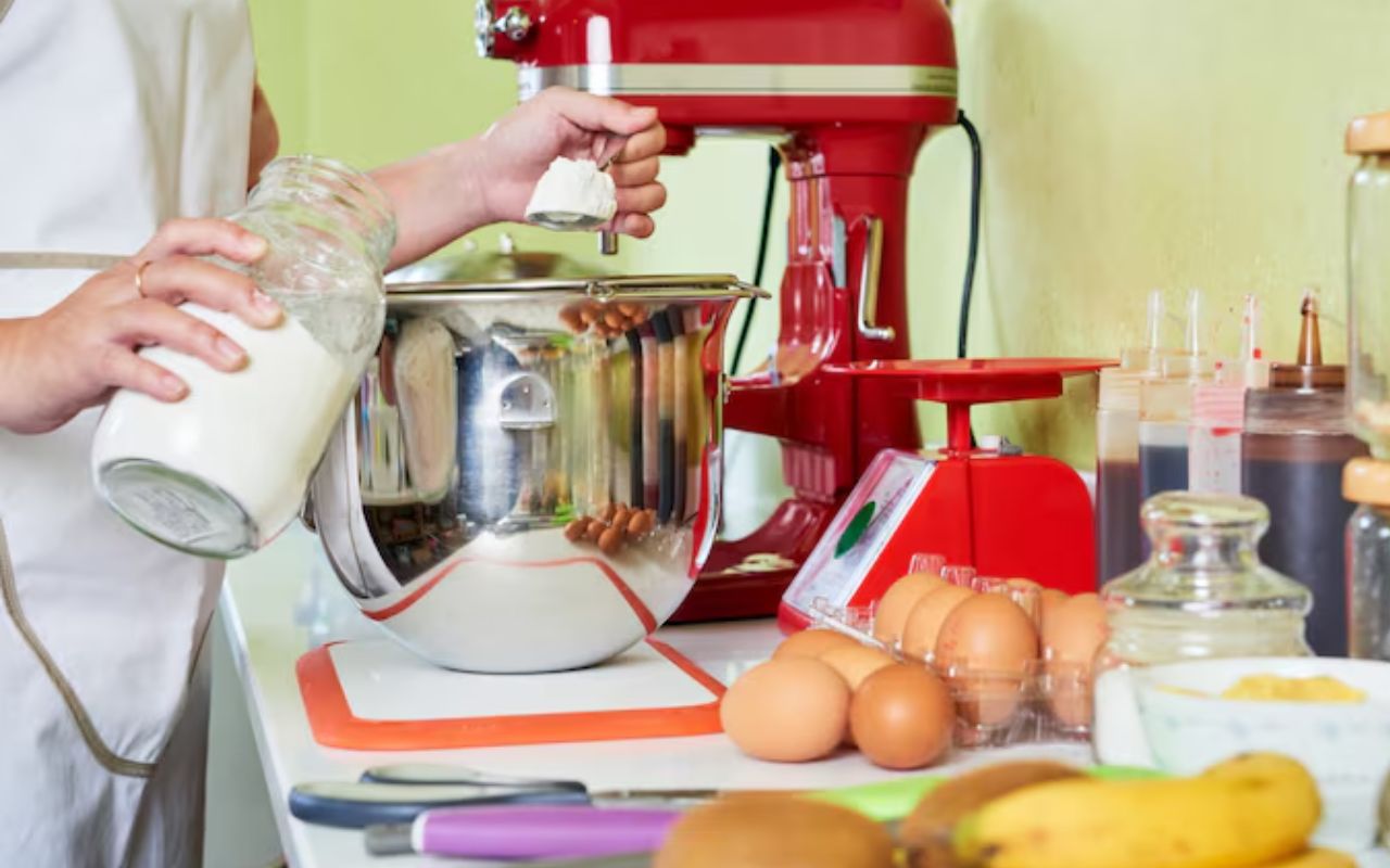 Person adding flour to a stand mixer bowl