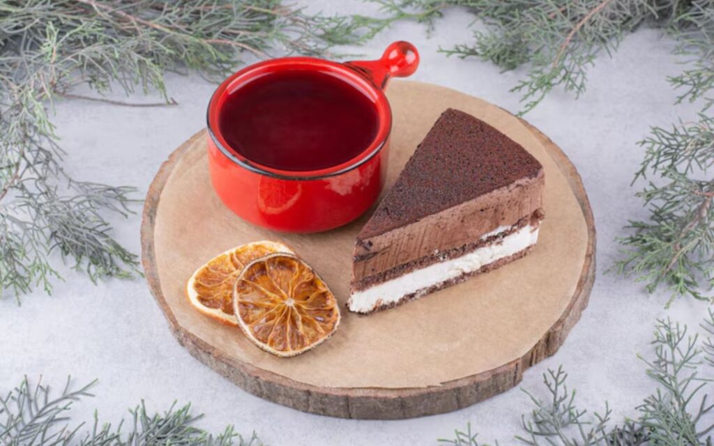 Chocolate cheesecake bar slice on wood board with a red mug