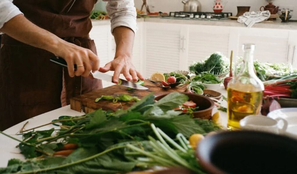 Person Slicing Vegetable on Brown Wooden Chopping Board