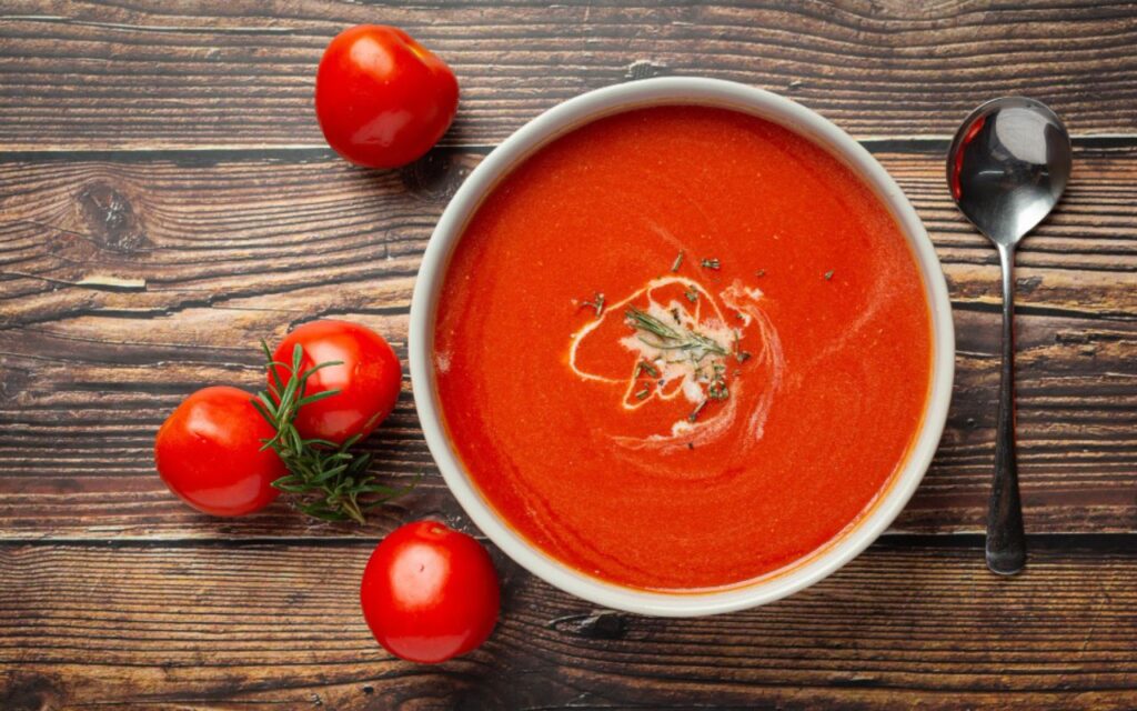 Bowl of creamy tomato soup with fresh tomatoes and herbs