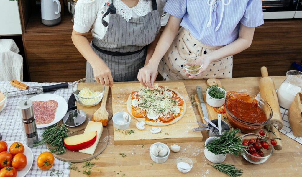 Women adding spices on pizza