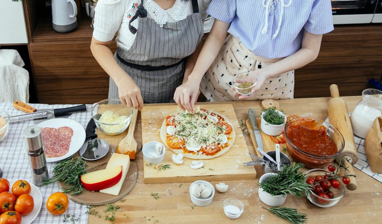 Women adding spices on pizza