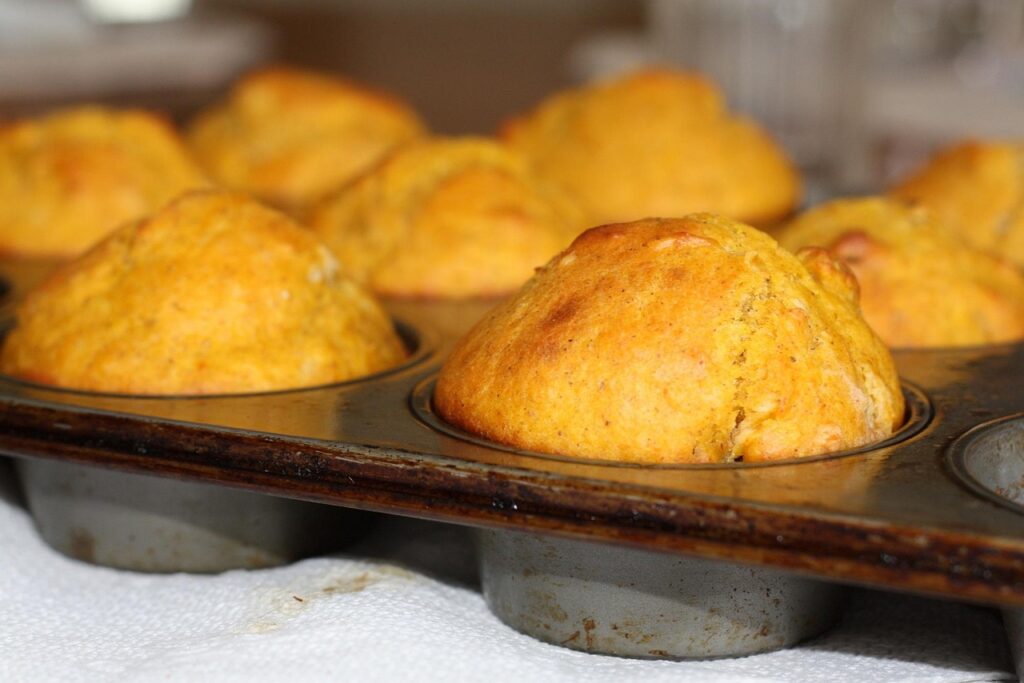 Tray of freshly baked biscuits and muffins cooling on a wooden rack.