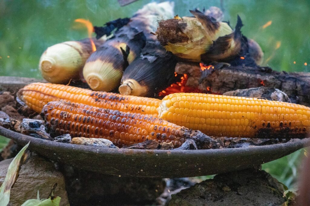 Charred corn directly over an open flame with tongs.
