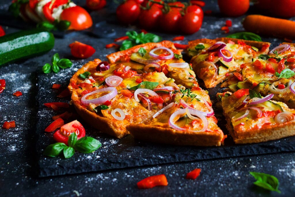 Overhead shot of a baked deep-dish pizza with a cut wedge and gooey cheese pull.