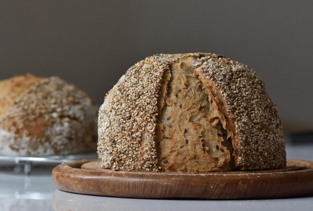 Close-up of a fresh loaf of bread with a rustic crust on a wooden table.