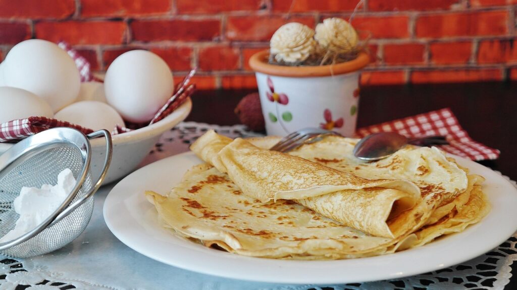 Stack of golden pancakes next to basic pantry ingredients.