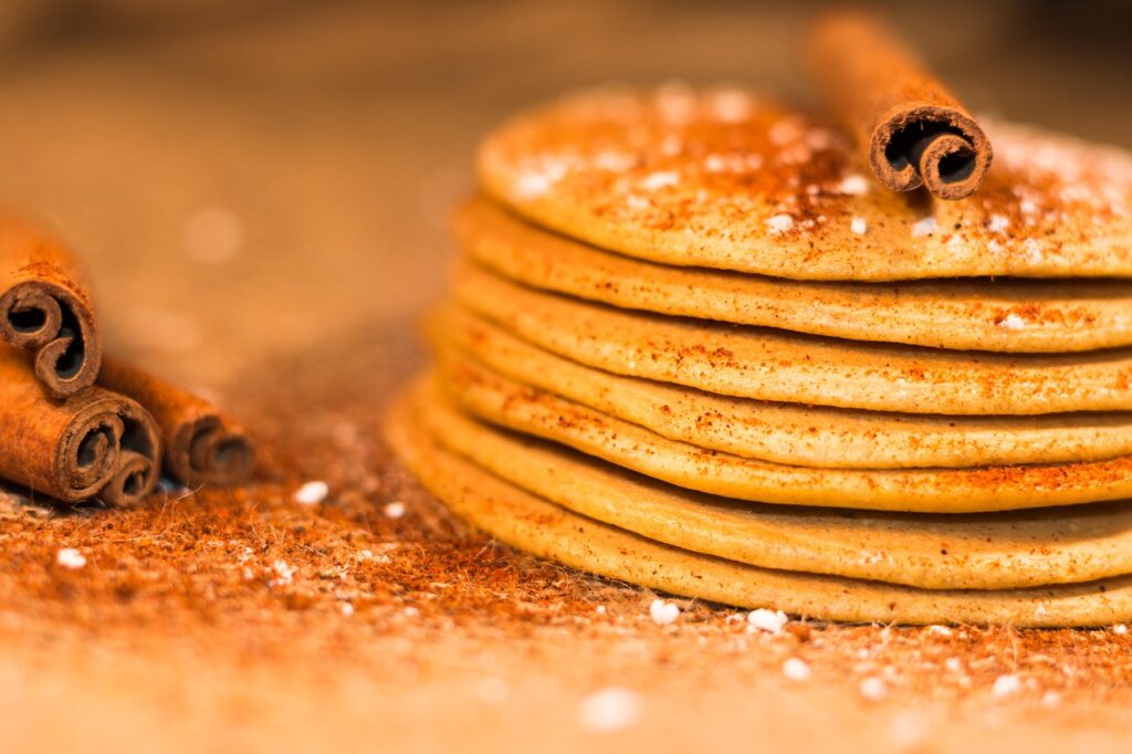 Sweet potato pancakes stacked on a plate with cinnamon dusting.