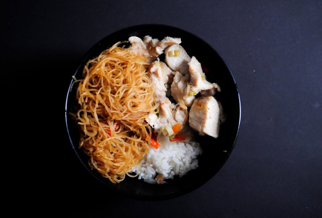 Bowl of thick chicken and noodles over mashed potatoes.