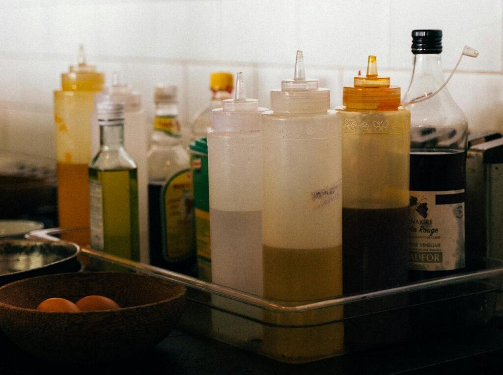 Bottles of oil and plastic sauce bottles on tray in kitchen