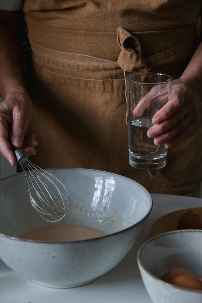 A bowl of batter next to an open bottle of sparkling water,