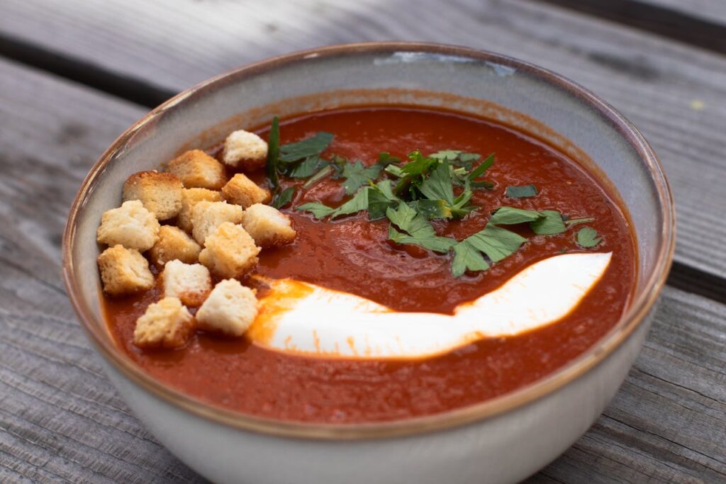 Bowls of soup topped with fresh herbs, croutons, or a swirl of cream.