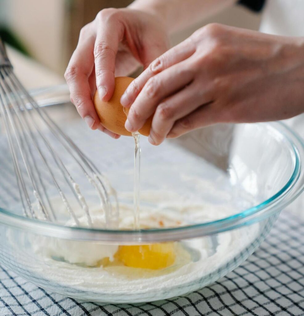  A close-up of cracked eggs with yolks in a glass bowl.