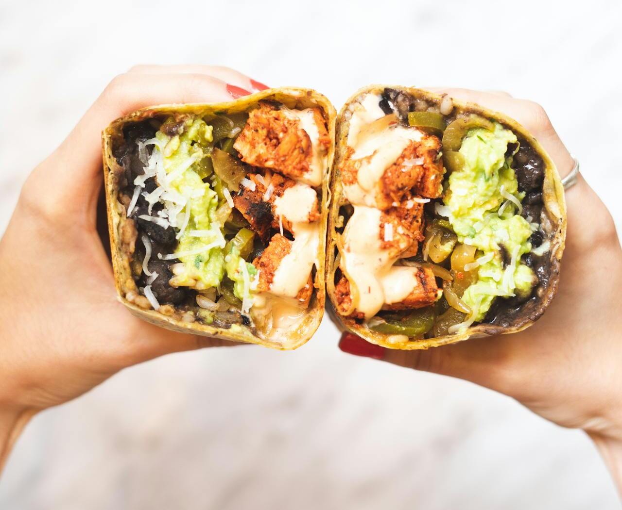 A cut-open burrito showing scrambled eggs, black beans, cheese, and salsa.