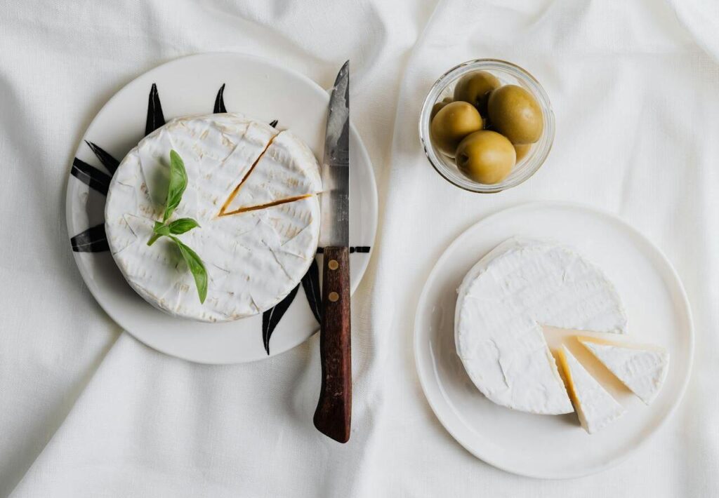 A wheel or wedge of Brie de Meaux on parchment with a knife nearby.