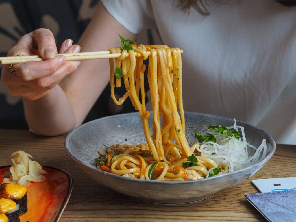 Thai peanut noodles in a bowl with chopsticks.