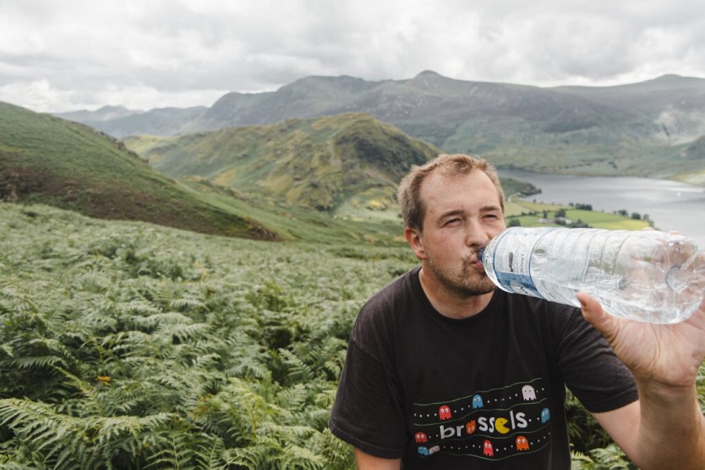 Male traveler drinking water in nature