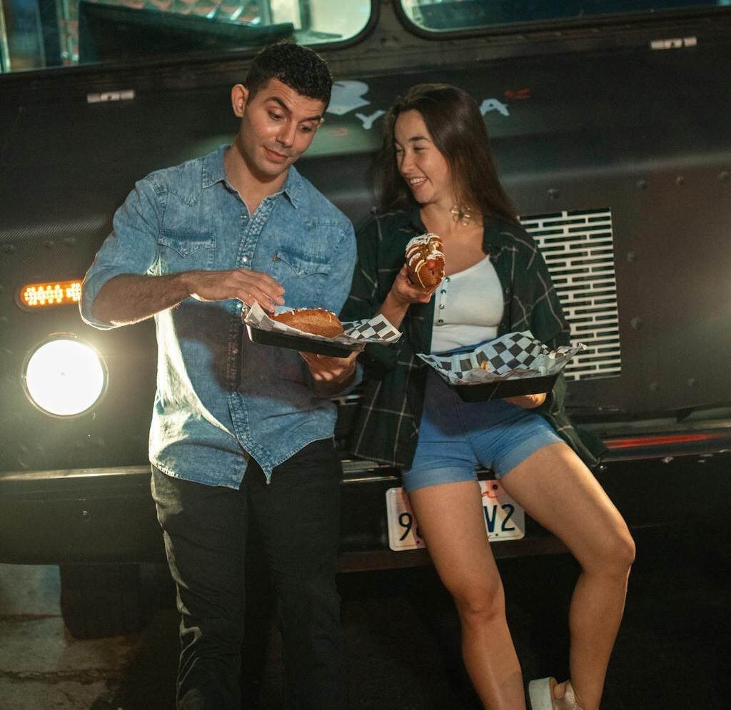 A Couple Leaning on a Food Truck while Having Conversation