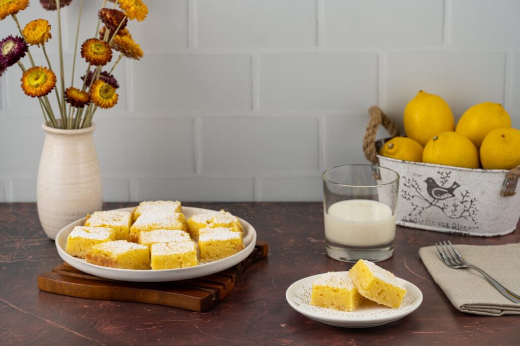 Bright lemon bars dusted with powdered sugar on a plate.