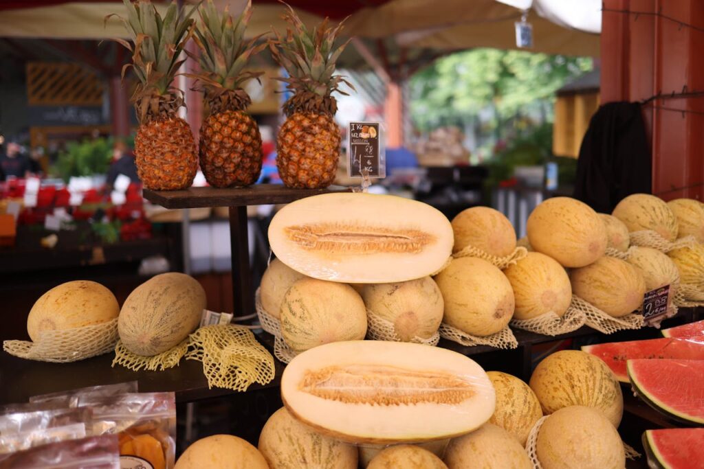 Fresh cantaloupes stacked at different ripeness stages in a market.
