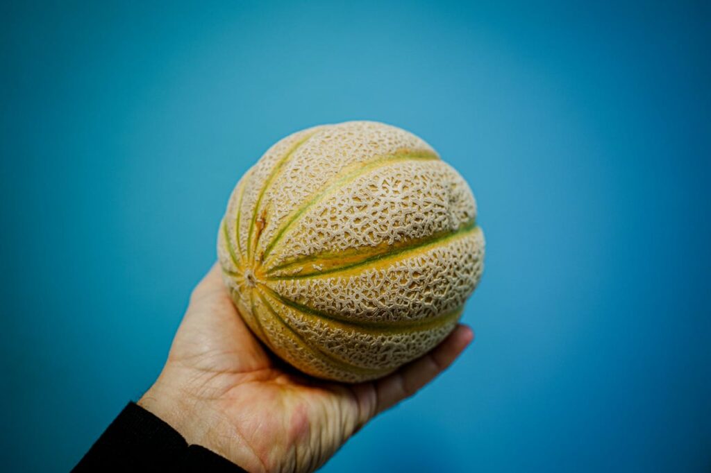 Hand feeling the rind for soft spots.