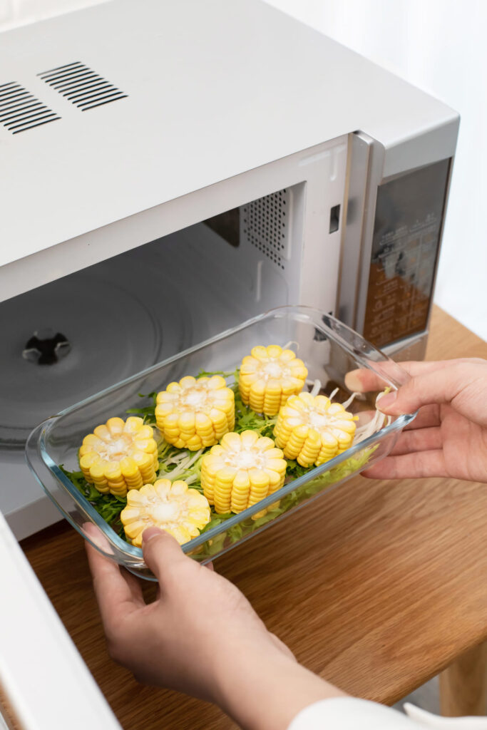 Hands carrying corn to the microwave