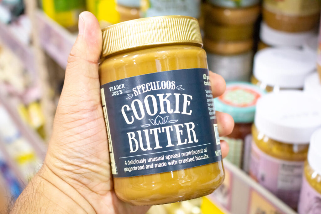 A view of a hand holding a jar of Speculoos Cookie Butter, on display at a local Trader Joe's store.