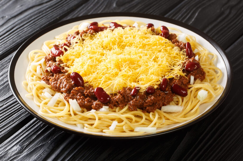 Cincinnati Chili: Spaghetti topped with chili and mounds of shredded cheddar cheese, served in a diner bowl.