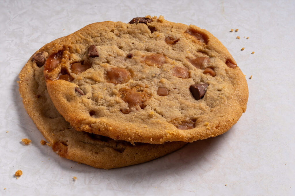 Homemade crunchy white milk chocolate chips and salted caramel cookies on a marble worktop. Close-up.