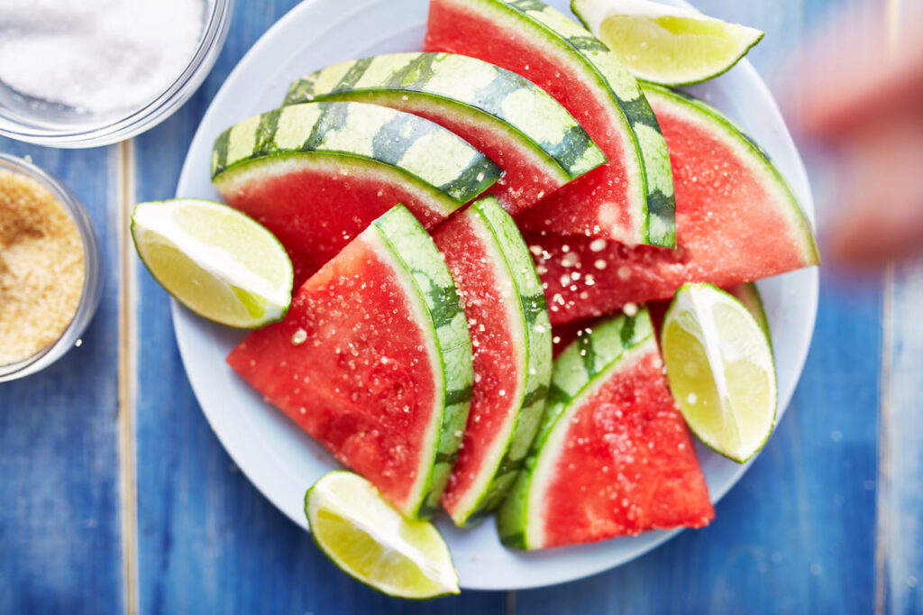 sprinkling salt on pile of watermelon slices