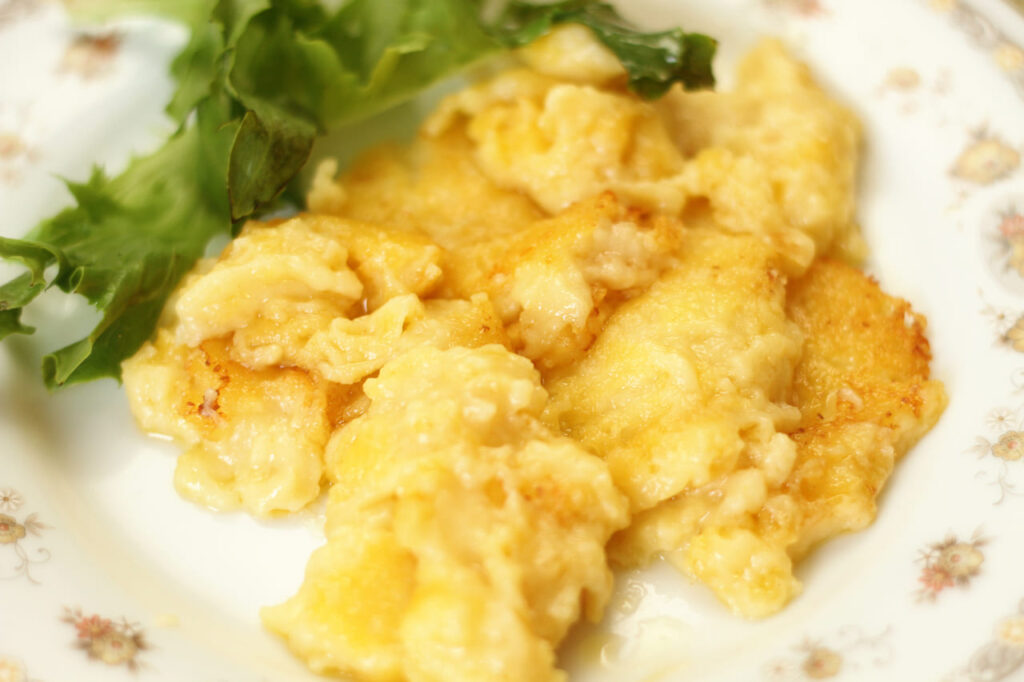 Corn mush fritters on a plate with lettuce. Unsuccessful cooking attempt. Shallow depth of field