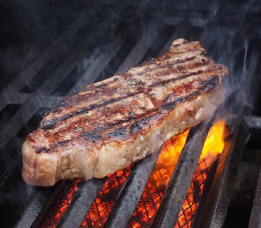 Flames licking up around a steak,