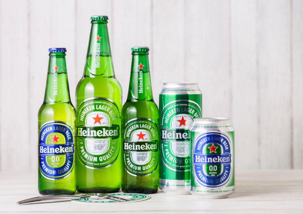 Bottles and aluminium cans of Heineken Lager Beer on wooden background.