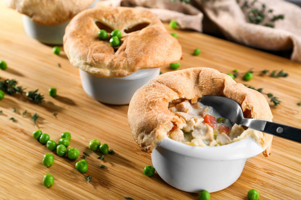Tasty baked chicken pot pie on wooden board