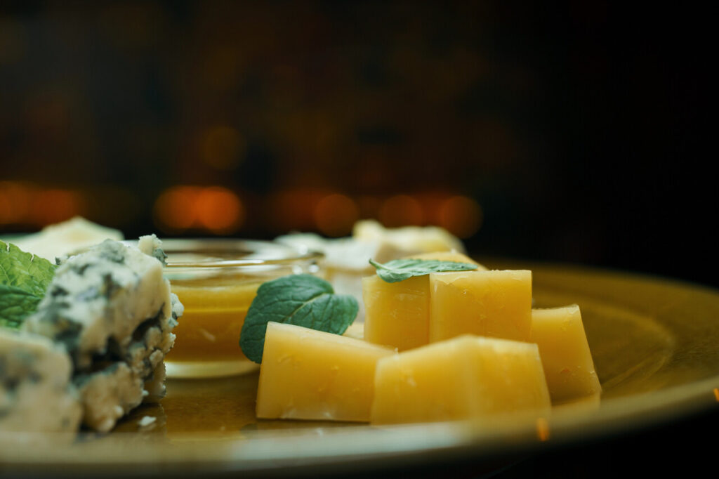 Tasting plate with two French cheeses, Parmesan and Roquefort cheese, served with sweet honey and mint leaves.