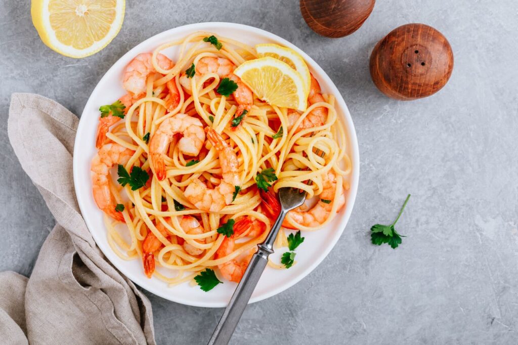 Seafood Pasta spaghetti with shrimps and parsley on gray stone background. 
