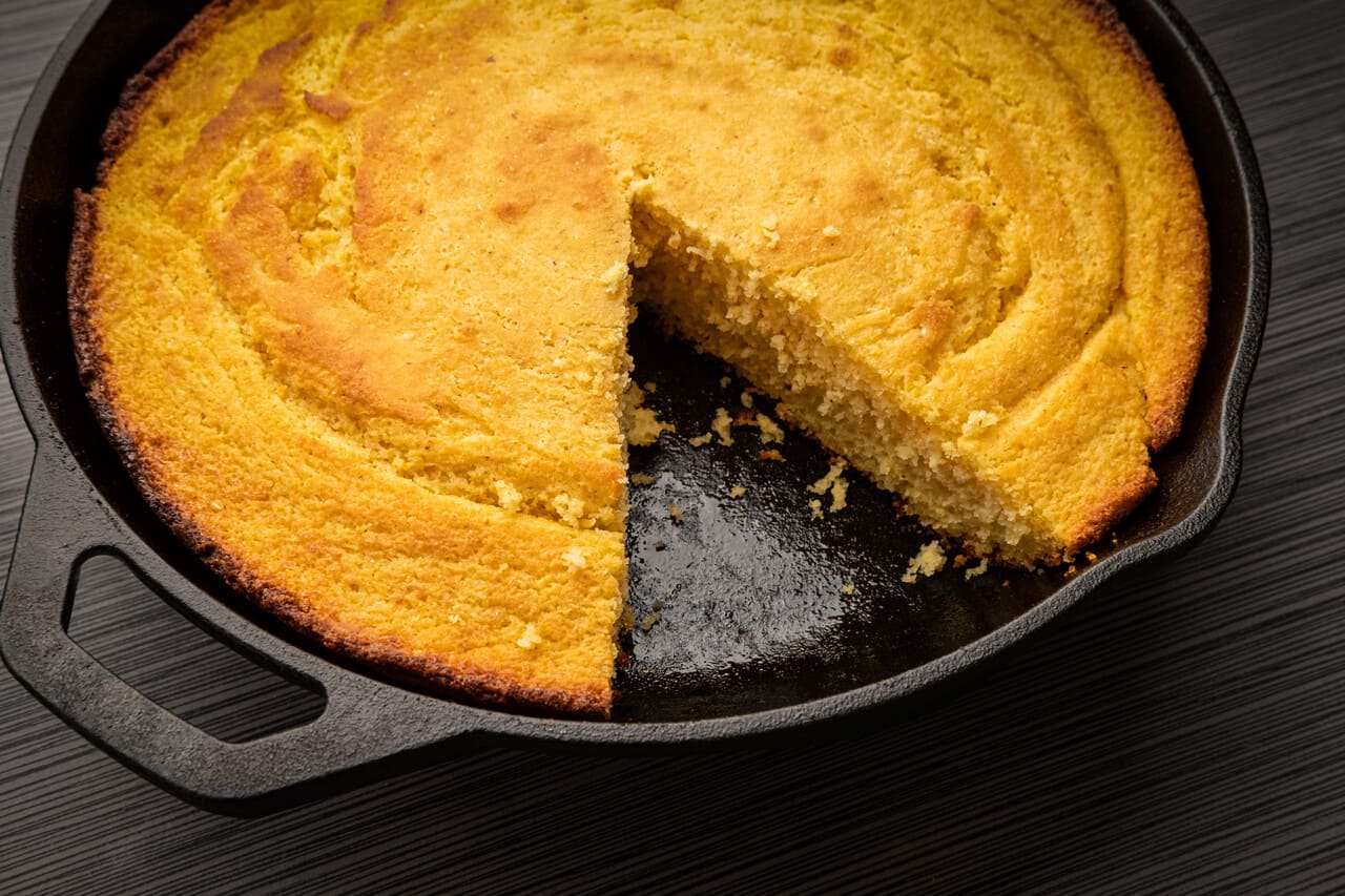 a single cast iron skillet of cornbread on a wooden table