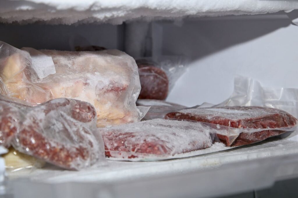 frozen meat packages in a freezer under the lights