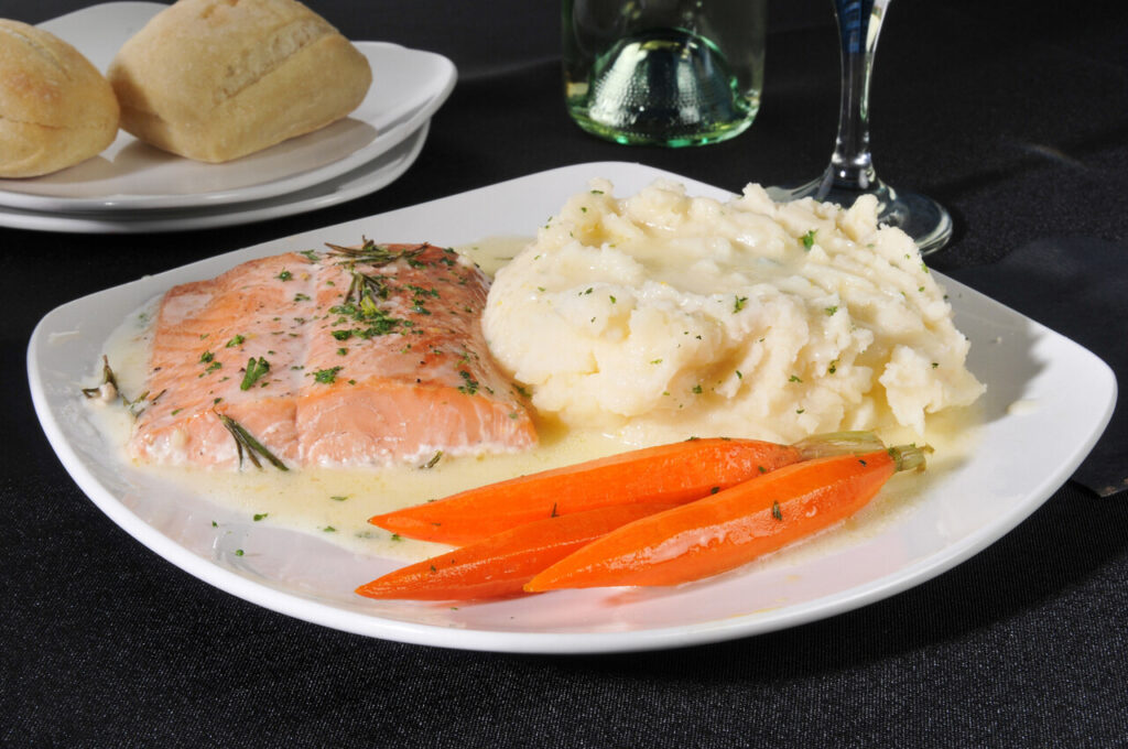 A baked salmon dinner with mashed potatoes and carrots