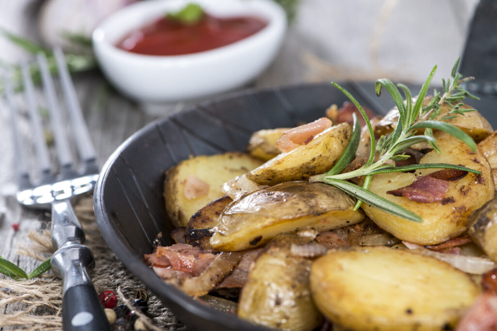 Portion of roasted Potatoes with bacon and fresh herbs