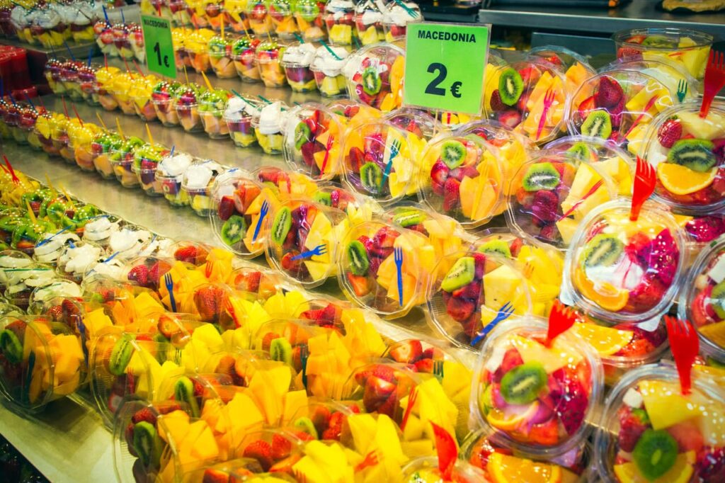 A supermarket aisle showcasing pre-cut fruit, salad kits, 