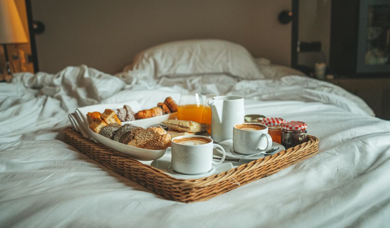 A tray of breakfast on a bed with white sheets