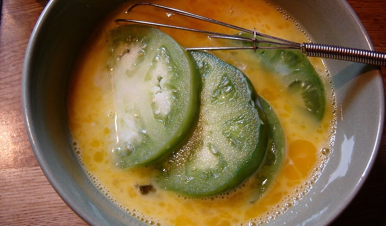 Green tomatoes in egg wash